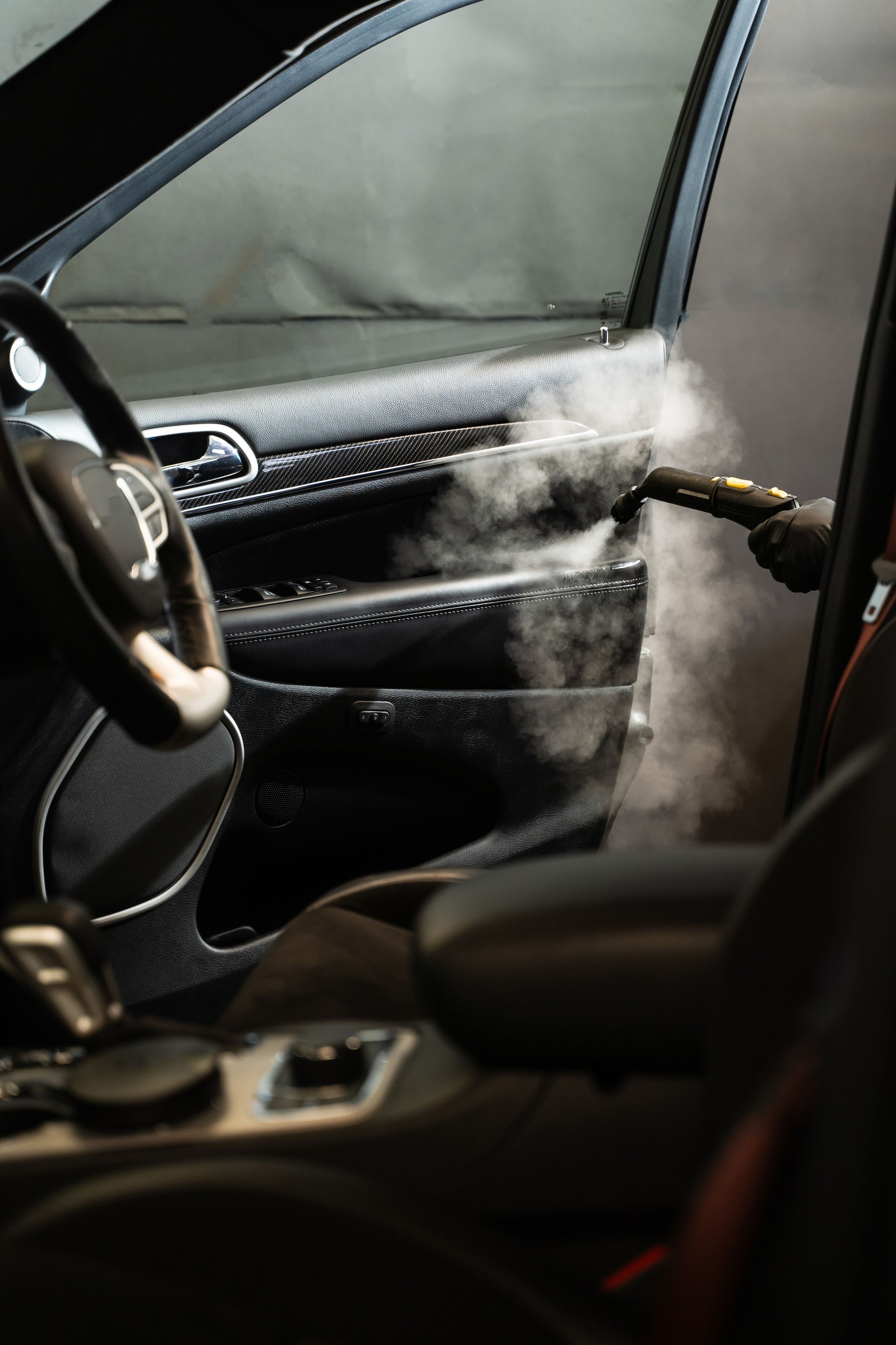 Removing stains and disinfecting car door. Cleaning and disinfecting by steam cleaner of the leather car interior.